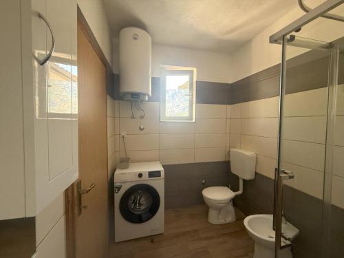 a bathroom with a washing machine and a toilet at Apartman mirna lokacija s pogledom i parkingom in Vodnjan