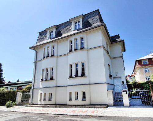 a white house with a black roof at Villa Patriot Apartmány in Mariánské Lázně