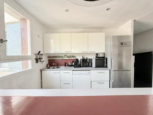 a kitchen with white cabinets and a stainless steel refrigerator at Appt Cosy Porte Paris parc Fleural et Parking in Saint-Maurice
