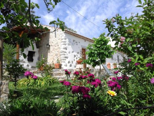 a garden in front of a white house with flowers at Quinta do Tempo Turismo Rural in Monchique
