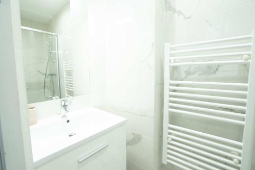 une salle de bain blanche avec un lavabo et un miroir dans l'établissement Logement terrasse metro Pierre Lachaise - 3P, à Paris