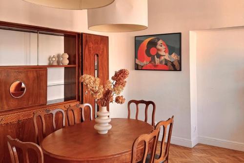 une salle à manger avec une table et un vase fleuri dans l'établissement Art Deco Retreat - Łódź Centrum, à Łódź