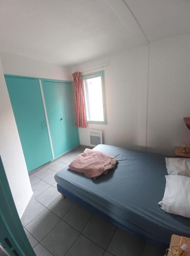 une chambre avec un lit bleu et une fenêtre dans l'établissement Logement Lazuli, à Argelès-sur-Mer