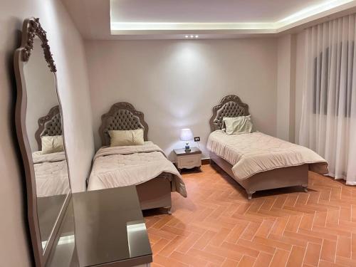 a bedroom with two beds and a mirror at Queen M in Marsa Matruh