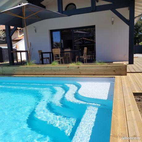 une piscine devant une maison dans l'établissement Villa Voltaire, à Seignosse