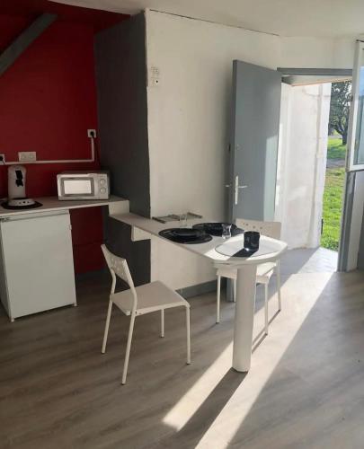 une cuisine avec une table et une chaise blanches dans l'établissement Le rustique, à Souligné-Flacé