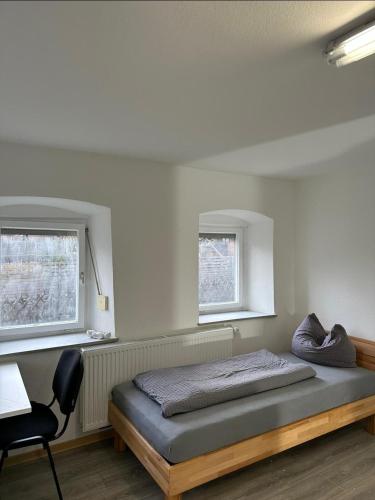 KönigsbronnにあるMonteurzimmer Königsbronn Dachgeschossのベッドと机と2つの窓がある寝室