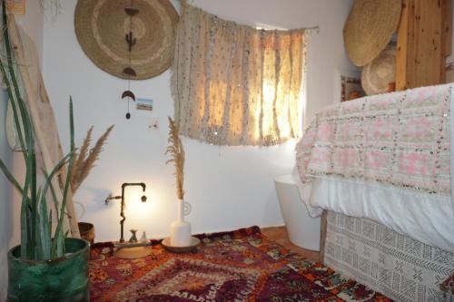 a bedroom with a bed and a table with a lamp at The Lunar Surf House in Tamraght Ouzdar