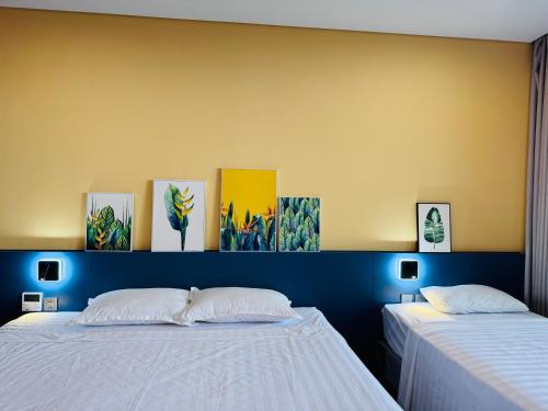 a bedroom with two beds and paintings on the wall at FLAMINGO Ibiza HaiTien - Ivy Abtel in Thanh Hóa