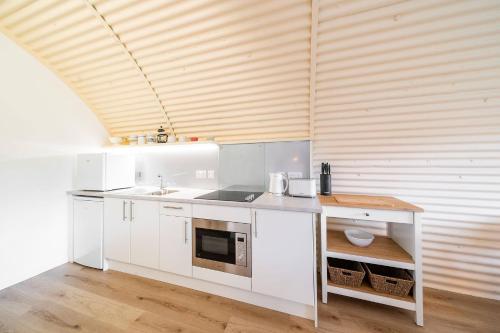 a kitchen with white cabinets and a wooden ceiling at Cultybraggan Hut 34 in Mill of Fortune