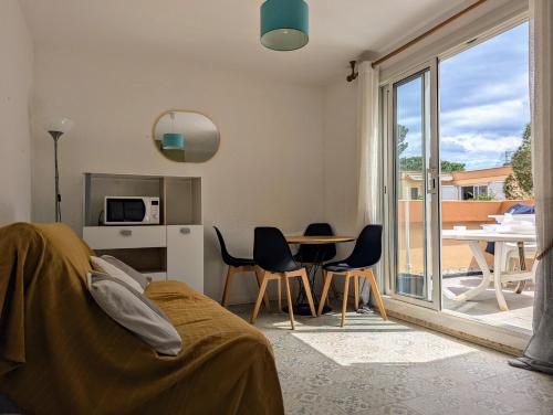 - une chambre avec une table et des chaises et un balcon dans l'établissement T2 climatisé avec terrasse à 200m de la plage, à Argelès-sur-Mer