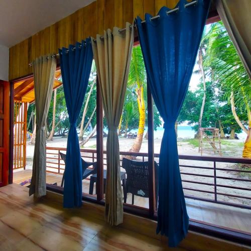 a room with a window with blue curtains at Lemon Grass Resort & Spa in Havelock Island