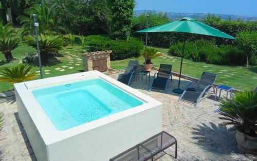 a large swimming pool with an umbrella and chairs at Agriturismo Tenuta Santa Maria in Notaresco