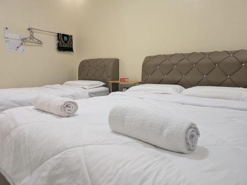 a group of white beds with towels on them at Din's Studio Homestay in Semporna
