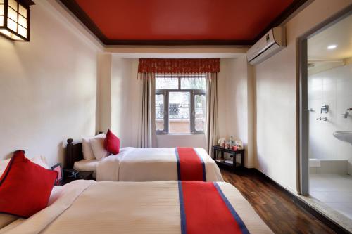 a hotel room with two beds and a bathroom at Shambaling Boutique Hotel in Kathmandu