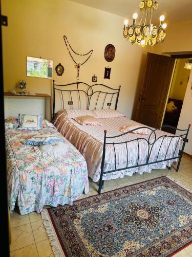 a bedroom with two beds and a chandelier at Il Giardino di Monterole Cà d'Pini in Bagnone