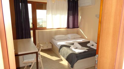 a small bedroom with a bed and a window at Апартамент Кабакум in Varna City