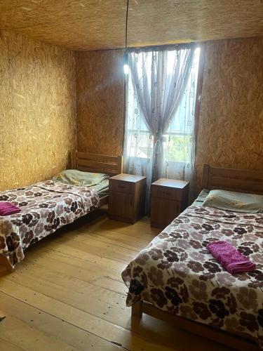 a bedroom with two beds and a window with curtains at Guest House Dora in Omalo
