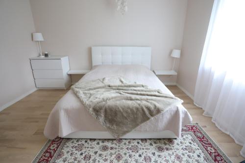 a white bedroom with a bed and a rug at Pinetree Villa in Haaslava