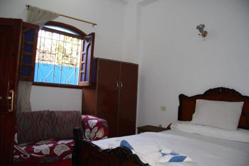 a bedroom with a bed and a window and a chair at One Love Guesthouse & Restaurant in Luxor