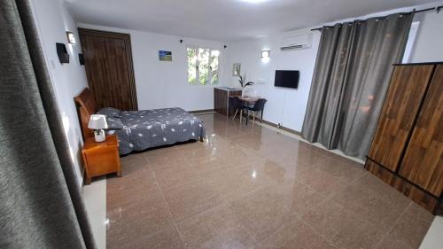 a room with a bed and a desk and a television at Soleil Vacances Bed and Breakfast in Flic-en-Flac