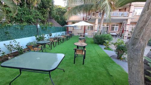 a patio with tables and chairs on the grass at Soleil Vacances Bed and Breakfast in Flic-en-Flac