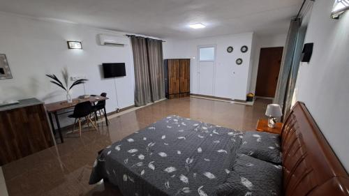a bedroom with a bed and a table and a desk at Soleil Vacances Bed and Breakfast in Flic-en-Flac