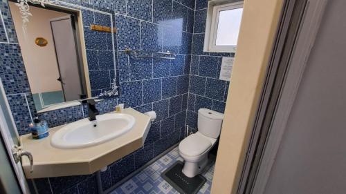 a blue tiled bathroom with a toilet and a sink at Soleil Vacances Bed and Breakfast in Flic-en-Flac