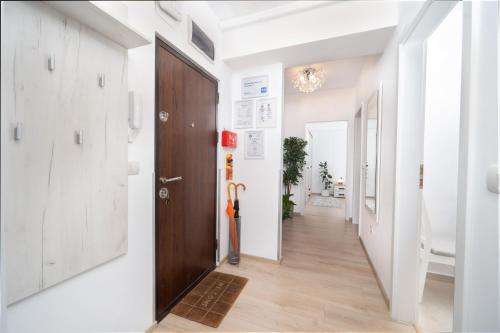 a hallway with a wooden door and white walls at Modern Apartment with Free Private Parking in Timisoara in Timişoara