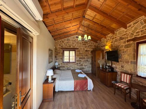 a bedroom with a bed and a stone wall at Archontiko Riziko in Kambos