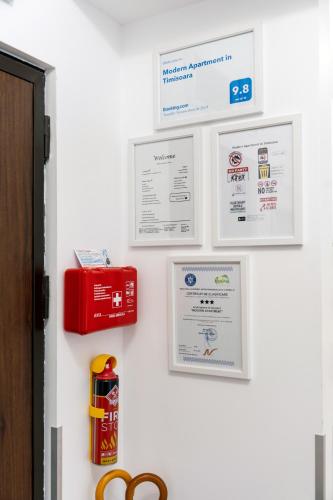 a white wall with certificates and signs on it at Modern Apartment with Free Private Parking in Timisoara in Timişoara