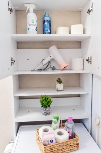 a closet with white shelves and a basket of toiletries at Modern Apartment with Free Private Parking in Timisoara in Timişoara