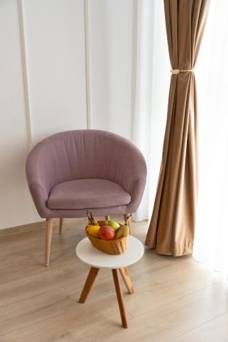 a purple chair with a bowl of fruit on a table at Modern Apartment with Free Private Parking in Timisoara in Timişoara