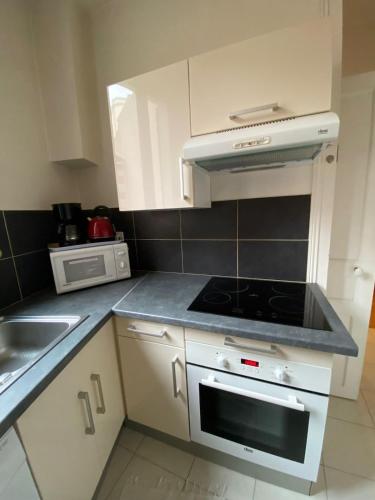 une cuisine avec des armoires blanches et un four à plaques de cuisson dans l'établissement Vichy MYRABA 2 Hypercentre, à Vichy