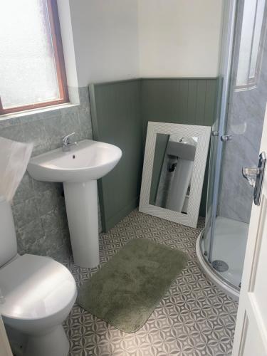 a bathroom with a sink and a toilet and a mirror at Prospect Beach House 2, Portstewart in Portstewart