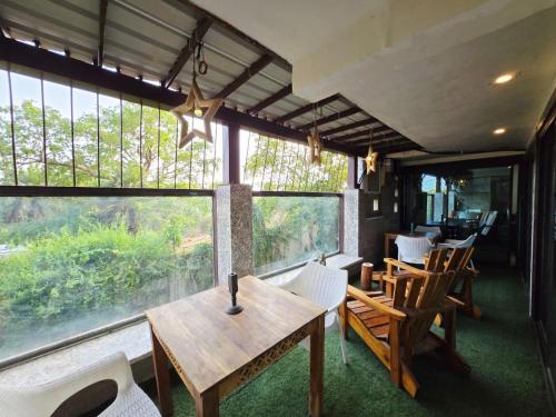 a dining room with a table and chairs and windows at Richhariya Nature's Retreat Homes in Jhānsi