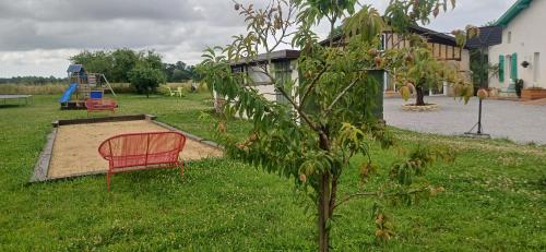 a red chair sitting in the grass next to a playground at Le petit Arrigade in Mimbaste