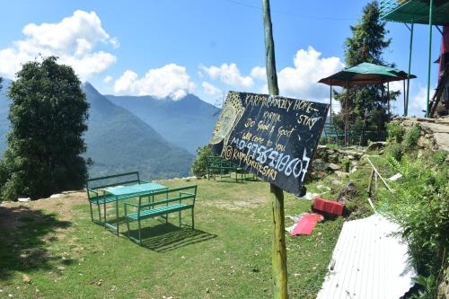 a sign on a hill with a table and benches at karmacafe in Chopta