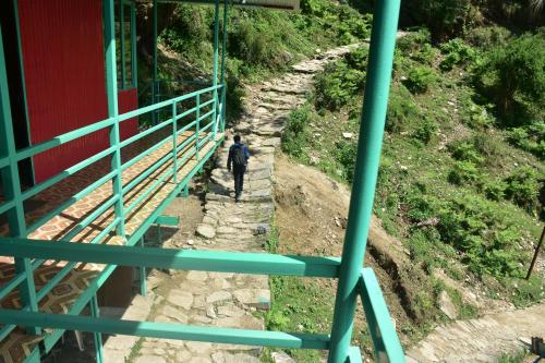 a man walking on a path under a bridge at karmacafe in Chopta