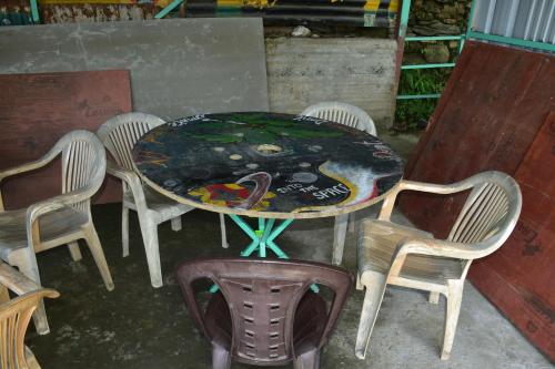 a table with chairs and a table with a painting on it at karmacafe in Chopta