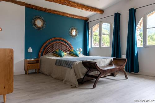 - une chambre avec un lit aux murs bleus et une chaise dans l'établissement Les LOGIS DE LA CHAPELLE classés 3 étoiles, à Roquebillière