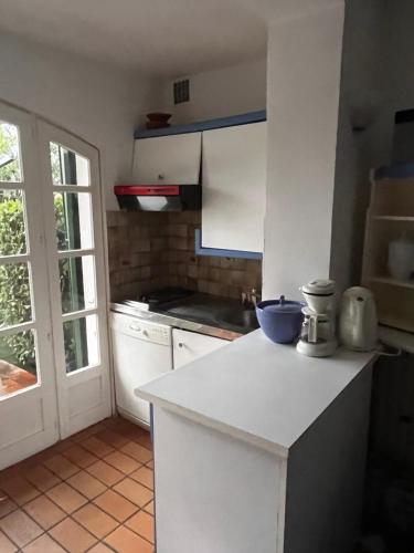 une cuisine avec un comptoir blanc et une fenêtre dans l'établissement appartement avec amarrage bateau jardin port grimaud, à Grimaud