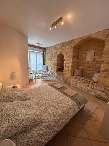 - une chambre avec un grand mur en pierre et un lit dans l'établissement Petite maison au pied du château, à Salignac Eyvigues