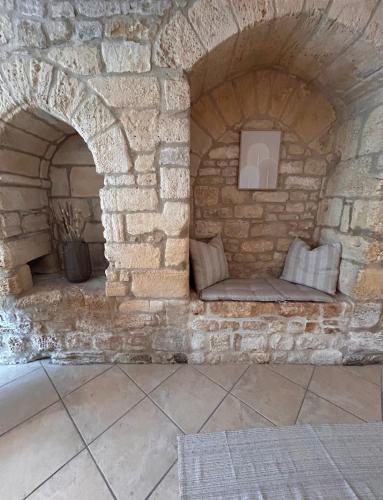 une cheminée en pierre avec un banc dans un mur en pierre dans l'établissement Petite maison au pied du château, à Salignac Eyvigues