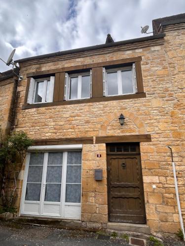 une maison en briques avec une porte et des fenêtres marron dans l'établissement Petite maison au pied du château, à Salignac Eyvigues