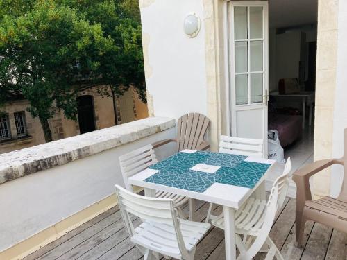 - une table et des chaises blanches sur une terrasse couverte dans l'établissement Bel appart t2 lumineux avec terrasse hyper centre., à La Rochelle