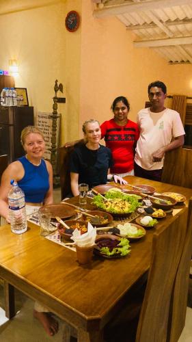 a group of people sitting around a table with food at Ayubowan Hiriketiya in Dickwella