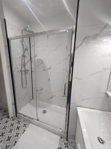 une douche avec une porte vitrée dans une salle de bain dans l'établissement Le Ponsardin, à Reims