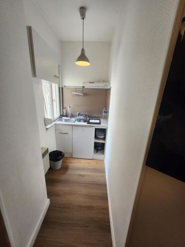 une petite cuisine avec des placards blancs et un couloir dans l'établissement Le Ponsardin, à Reims