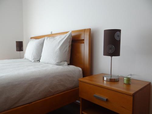 una camera con letto e lampada sul comodino di Quartos, Solar da São a Nazaré